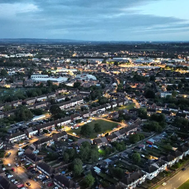 An aerial dusk view of a residential town with rows of houses, roads and a green space