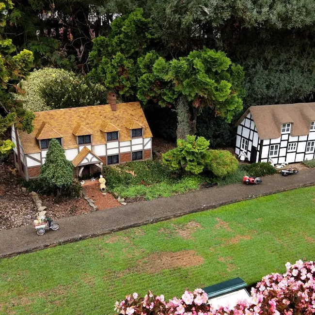 Aerial view of a miniature model village with small thatched houses, trees and figures