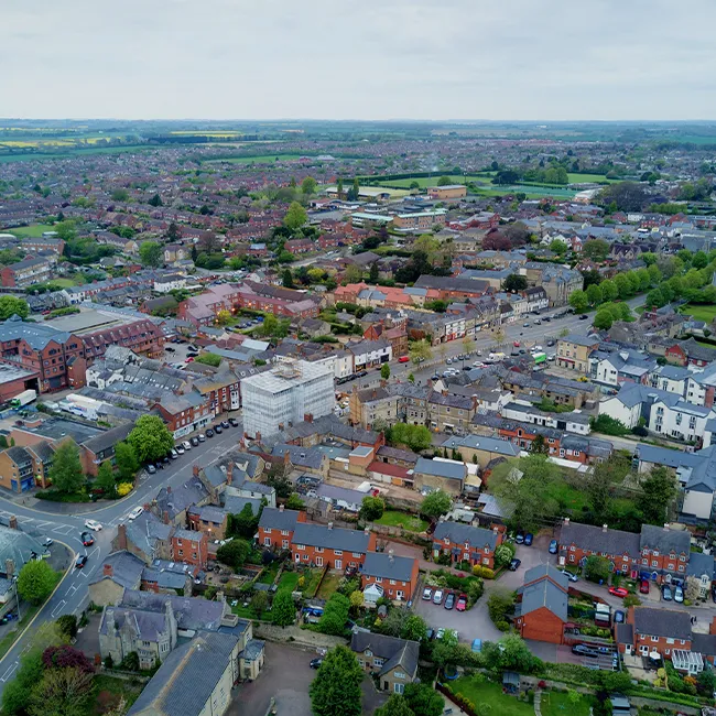 Aerial view of a town centre high street with shops, houses and surrounding countryside