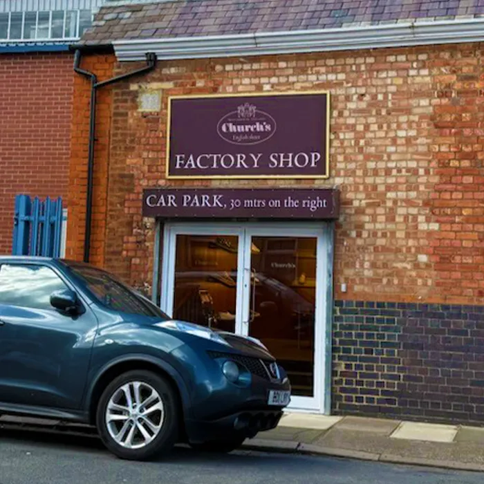 Shopfront signage reading 'Church's Factory Shop' and 'Car park, 30 mtrs on the right', with a car parked outside