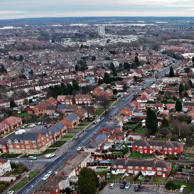 Aerial view of a residential suburb with rows of terraced houses and a tall tower block in the distance