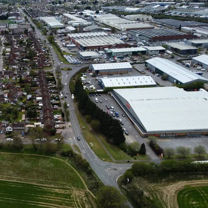 Aerial view of an industrial estate with warehouses and roads, housing and fields beyond