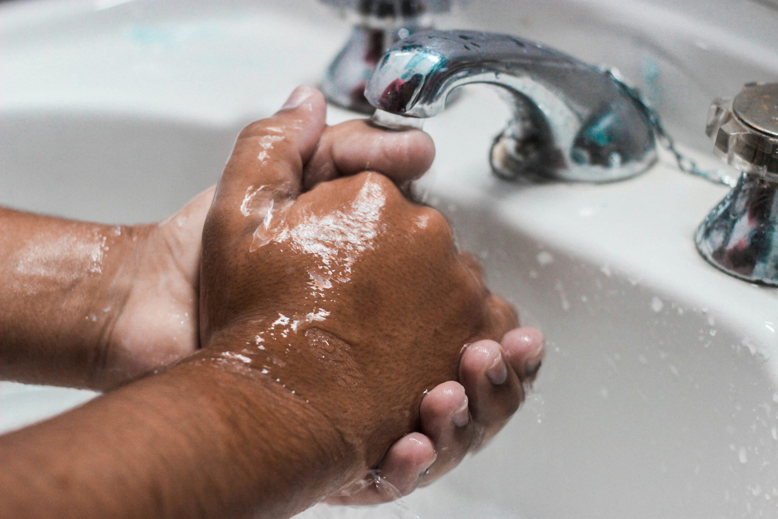 Close-up of hands being washed with soap under a running tap