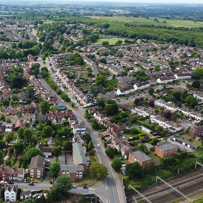 Aerial view of a suburban residential area with terraced houses, tree-lined roads and a railway line