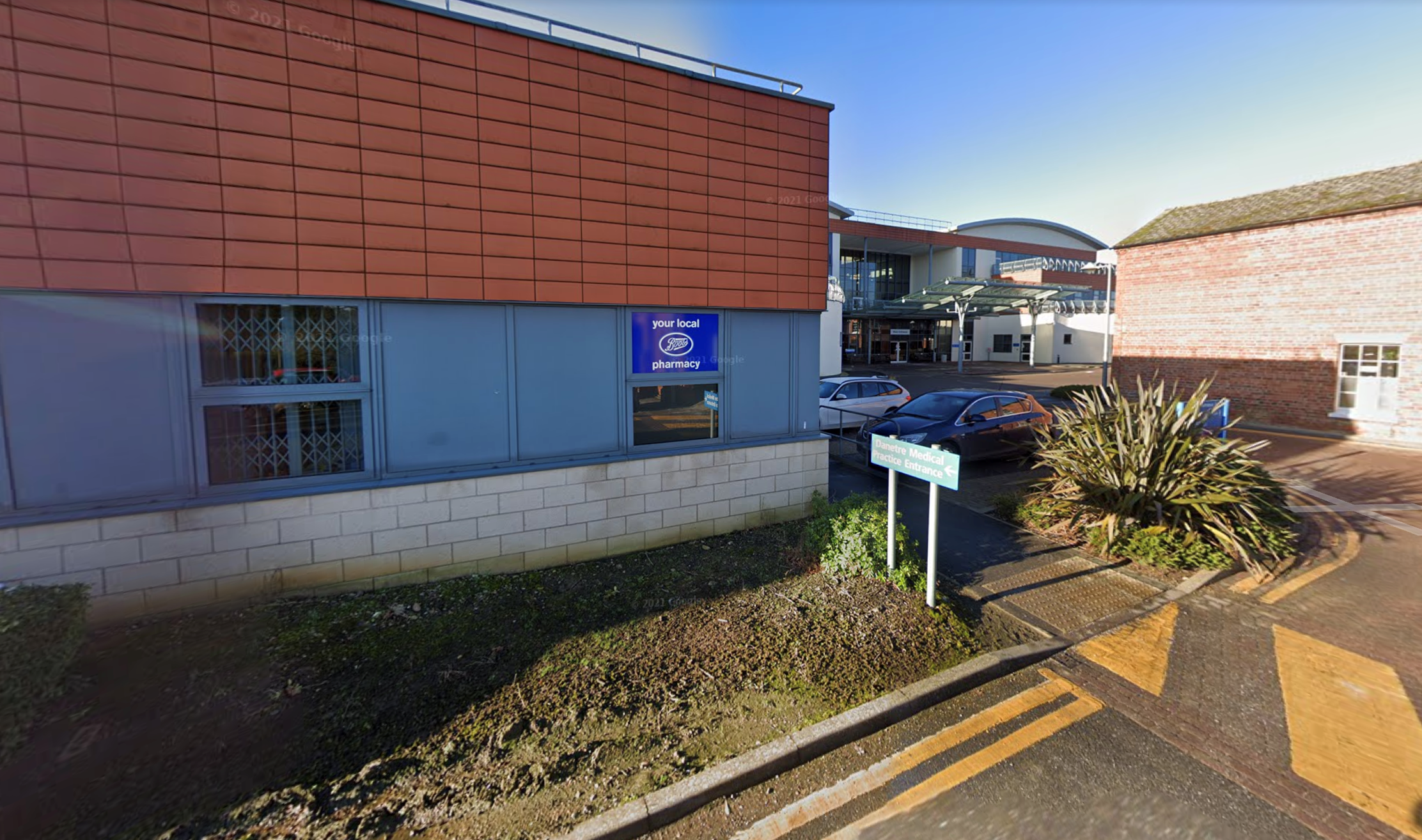 A red-brick medical building with a pharmacy sign and car park signage