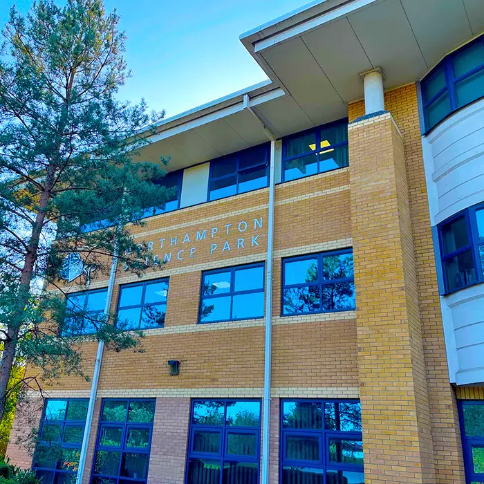 A multi-storey brick office building with dark-framed windows and partial signage on the facade